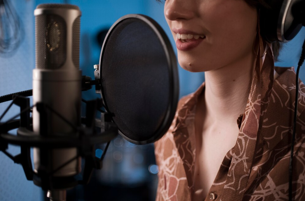 a woman in a brown shirt sings into a microphone