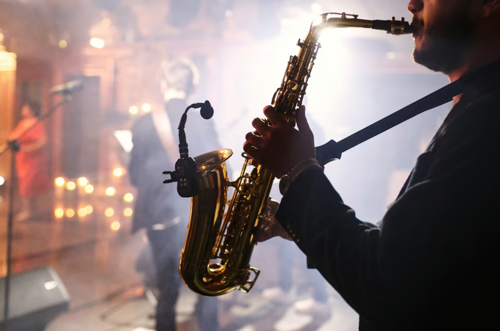 man plays a saxophone on the stage, other stands facing the public