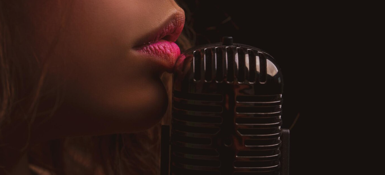 closeup photo of a woman close to the microphone on a black background