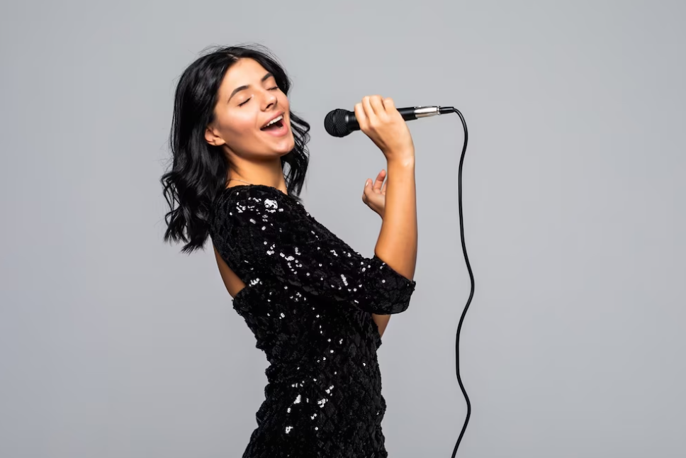 woman in a shiny black dress and closed eyes singing with microphone